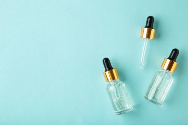 Yağlı pipetli cam şişeler, mavi arkaplanda fotokopi alanı olan serum. Flatlay. Üst görünüm