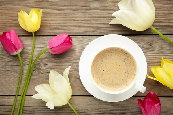 Cup of coffee with tulips on grey background with copy space. Top view