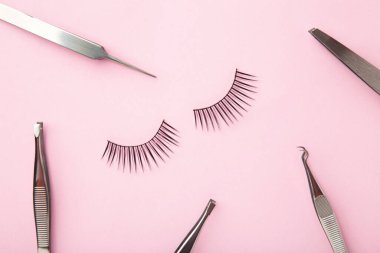 Pembe arka planda cımbızlı takma kirpik seti. Minimalizm. Üst görünüm