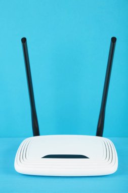 Mavi arka planda siyah antenli beyaz kablosuz yönlendirici ve kopyalama alanı. Minimalizm. Üst görünüm