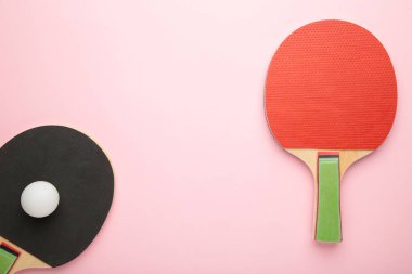 Pembe arka planda pinpon raketleri ve top. Üst görünüm