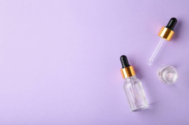 Yağlı pipetli cam şişeler. Mor zemin üzerinde fotokopi alanı olan serum. Flatlay. Üst görünüm