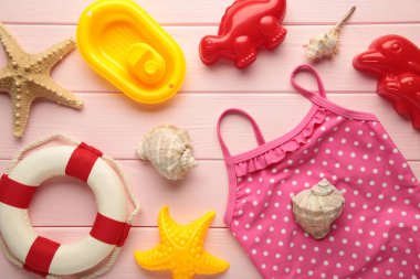 Pembe arka planda aksesuarları olan yaz plaj oyuncakları. Üst görünüm