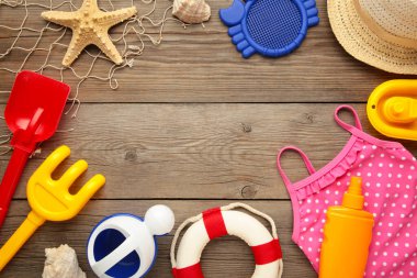 Gri ahşap arka planda aksesuarları olan yaz plaj oyuncakları. Üst görünüm