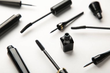 Gri arka planda siyah göz kalemlerini ve rimel fırçasını kapat. Üst görünüm.