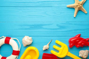Mavi arka planda aksesuarları olan yaz plaj oyuncakları. Üst görünüm