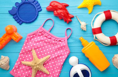 Mavi arka planda aksesuarları olan yaz plaj oyuncakları. Üst görünüm