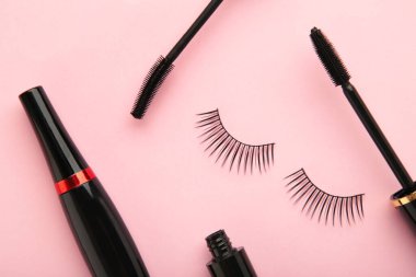 Siyah göz kalemlerini ve pembe arka planda rimel fırçasını kapat. Üst görünüm.