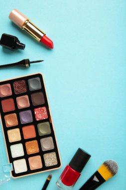 Mavi arka planda dekoratif kozmetik ürünler. Makyaj. Dikey fotoğraf. Üst görünüm