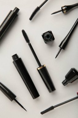 Gri arka planda siyah göz kalemlerini ve rimel fırçasını kapat. Üst görünüm.
