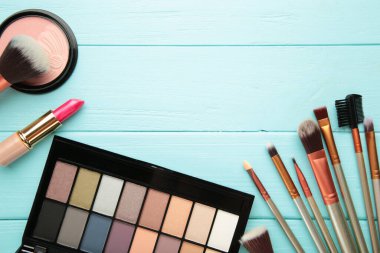 Mavi arka planda farklı lüks makyaj ürünleri var. Üst görünüm