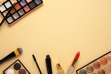 Bej arka planda farklı lüks makyaj ürünleri, düz yatış. Üst görünüm