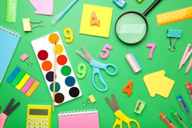 Yeşil arka planda okul malzemeleri. Üst görünüm.