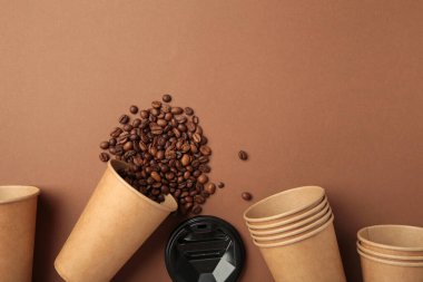 Kahverengi arka planda kahve çekirdekleri ve kağıt kahve fincanları. Üst görünüm.