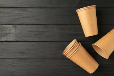 Siyah ahşap arka planda tek kullanımlık kağıt bardaklar. Üst görünüm.