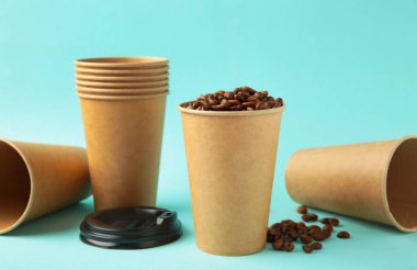 Kahve çekirdekleri ve mavi arka planda kağıt kahve fincanı. Üst görünüm.