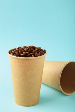 Kahve çekirdekleri ve mavi arka planda kağıt kahve fincanı. Üst görünüm.