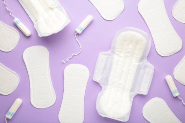 Mor bir arka planda regl tamponları ve pedler. Adet döngüsü. Hijyen ve koruma. Üst görünüm.