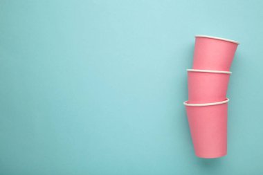 Mavi arkaplanda tek kullanımlık pembe kağıt bardaklar.