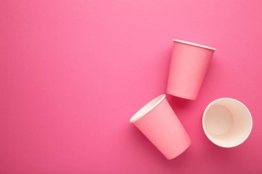 Pembe arka planda tek kullanımlık kağıt bardaklar.