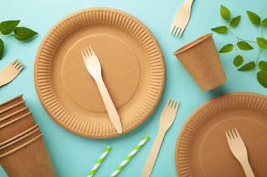 Mavi arka planda yeşil yapraklı tek kullanımlık çevre dostu yemekler. Sıfır atık, çevre dostu, plastikten arınmış. Üst görünüm