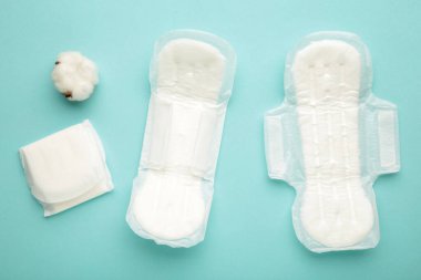 Beyaz hijyenik ped, arka planda hijyen koruması. Jinekolojik adet döngüsü. Bir gül çiçeği adet yastığında yatar. İlk regl. Dikey fotoğraf