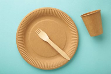 Eko kağıt sofra takımı. Kâğıt bardaklar, tabaklar, çantalar, fast food kapları ve mavi arka planda ahşap çatal bıçak takımı. Sıfır kayıp. Geri dönüşüm konsepti. Boşluğu kopyala