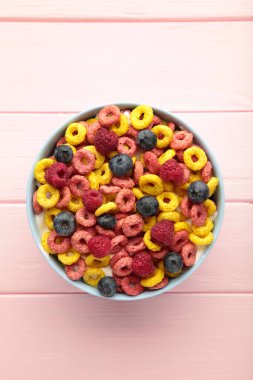 Bir kase mısır gevreği ve pembe arka planda taze böğürtlen. Üst görünüm.