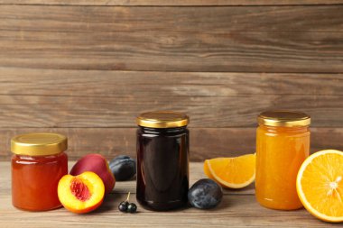 Gri ahşap arka planda kavanozda ev yapımı meyve reçeli.