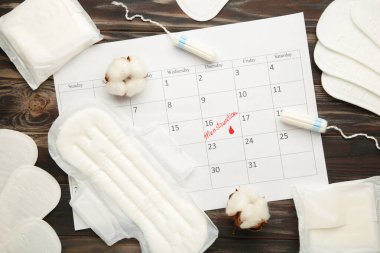 Kahverengi arka planda pamuk tamponlar ve pedlerle regl takvimi. Üst görünüm