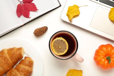 Sıcak çay ve sonbahar yaprakları beyaz üzerine defter ile - mevsimsel rahatlama kavramı. Üst görünüm