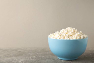 Gri arka planda bir kasede ev yapımı süzme peynir. Üst görünüm