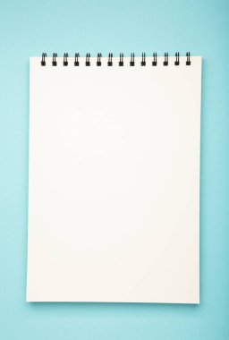 White spiral notebook mockup on blue background. Top view