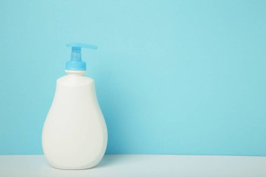 Mavi arka planda beyaz plastik bir şişe sıvı sabun. Üst görünüm