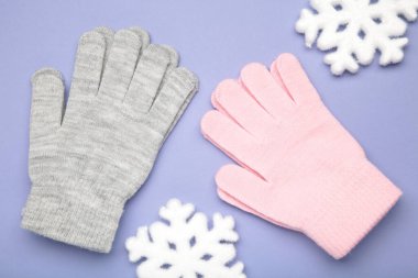 Mor arka planda beyaz kar taneleri olan sıcak yün eldivenler. Metin için boşluk