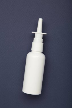 Koyu mavi arka planda burun spreyi şişesi. Üst görünüm