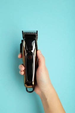 Mavi arka planda elinde saç makasıyla. Modern saç makası. Dikey fotoğraf. Üst görünüm