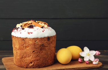 Geleneksel paskalya pastaları, renkli serpiştirilmiş yumurta, tavşan heykeli ve siyah arka planda bahar çiçekleri.