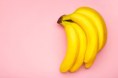 Sarı muzlar pembe arka planda yatıyordu. Üst görünüm