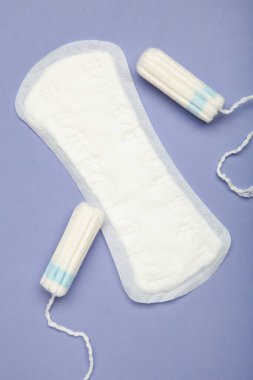 Mor arka planda regl pedi ve tampon. Üst görünüm