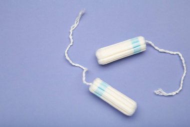 Mor arka planda kadınların hijyen dönemi için pamuk tamponlar. Metin için boşluk