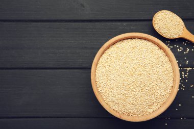 Tabakta organik beyaz kinoa tohumu ve siyah ahşap arka planda kaşık. Metin için boşluk