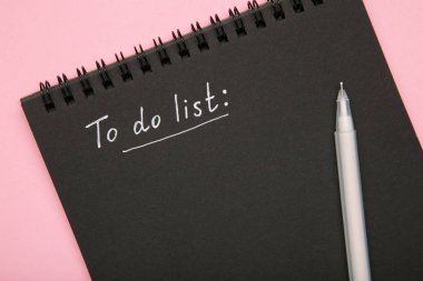 Siyah deftere pembe arka planda beyaz kalemle liste yapmak için. Üst görünüm