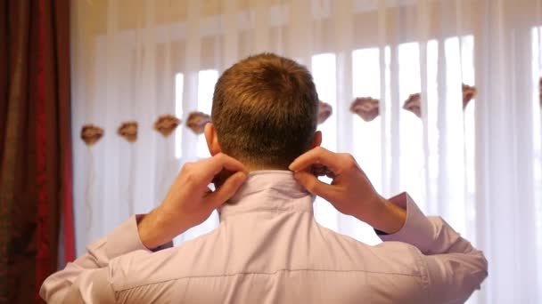 Man (the groom) raises collar shirt — Stock Video