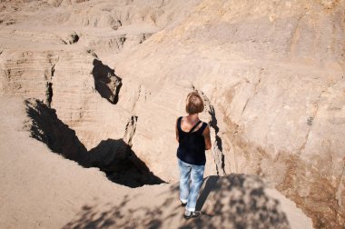 Uçurumun kenarında duran bir kadın. Derin vadiler, tepecikleri aşındıran bahar nehirlerinden oluşur.. 
