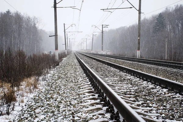 Railroad into foggy distance. Bad weather and snow changed an ordinary landscape