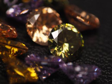 Güzel, parlak, çok renkli elmas kristal değerli taşların yakın plan çekimleri, arka plan olarak siyah deri üzerine çekim