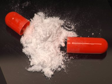 Beyaz ilaç ilacı içeren turuncu kapsülün yakın plan görüntüsü.