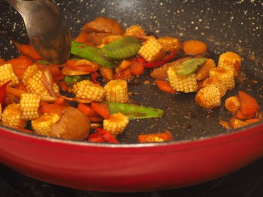 Karıştırmak için gümüş kaşıkla tavada pişmiş bebek mısırı.