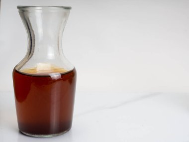 Ahşap bir masanın üzerinde bir fincan buzlu kahve ve bir kavanoz kabı. Karanlık ruh hali tarzında ateş et.